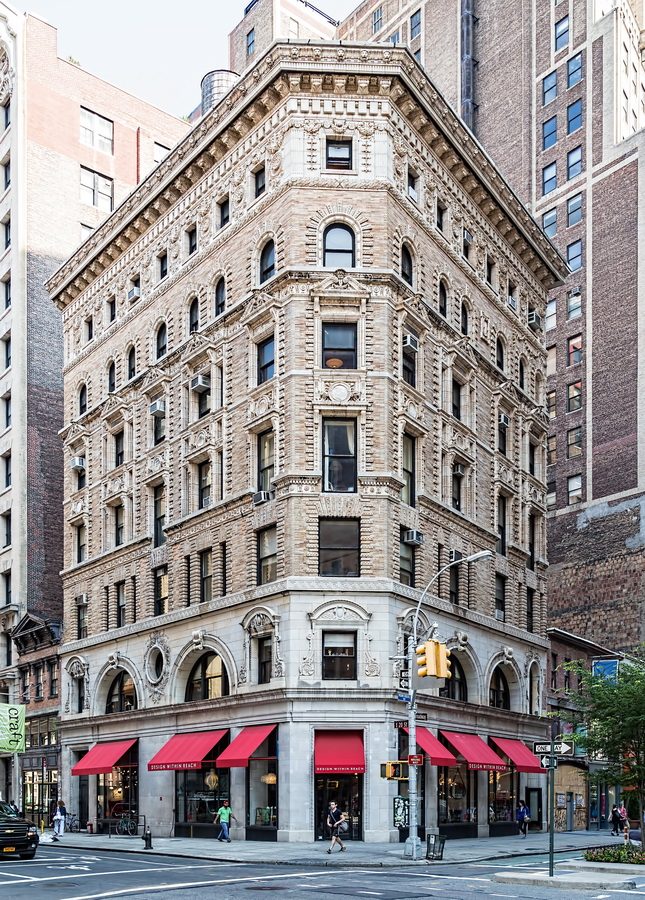 The Warren Building at 907 Broadway, a Romanesque limestone corner building with red awnings